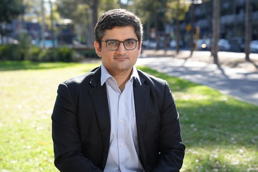 A close-up of a man wearing a suit sitting on a park bench.